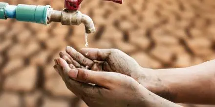 Dos manos intentando conseguir algo de un grifo que echa muy poca agua